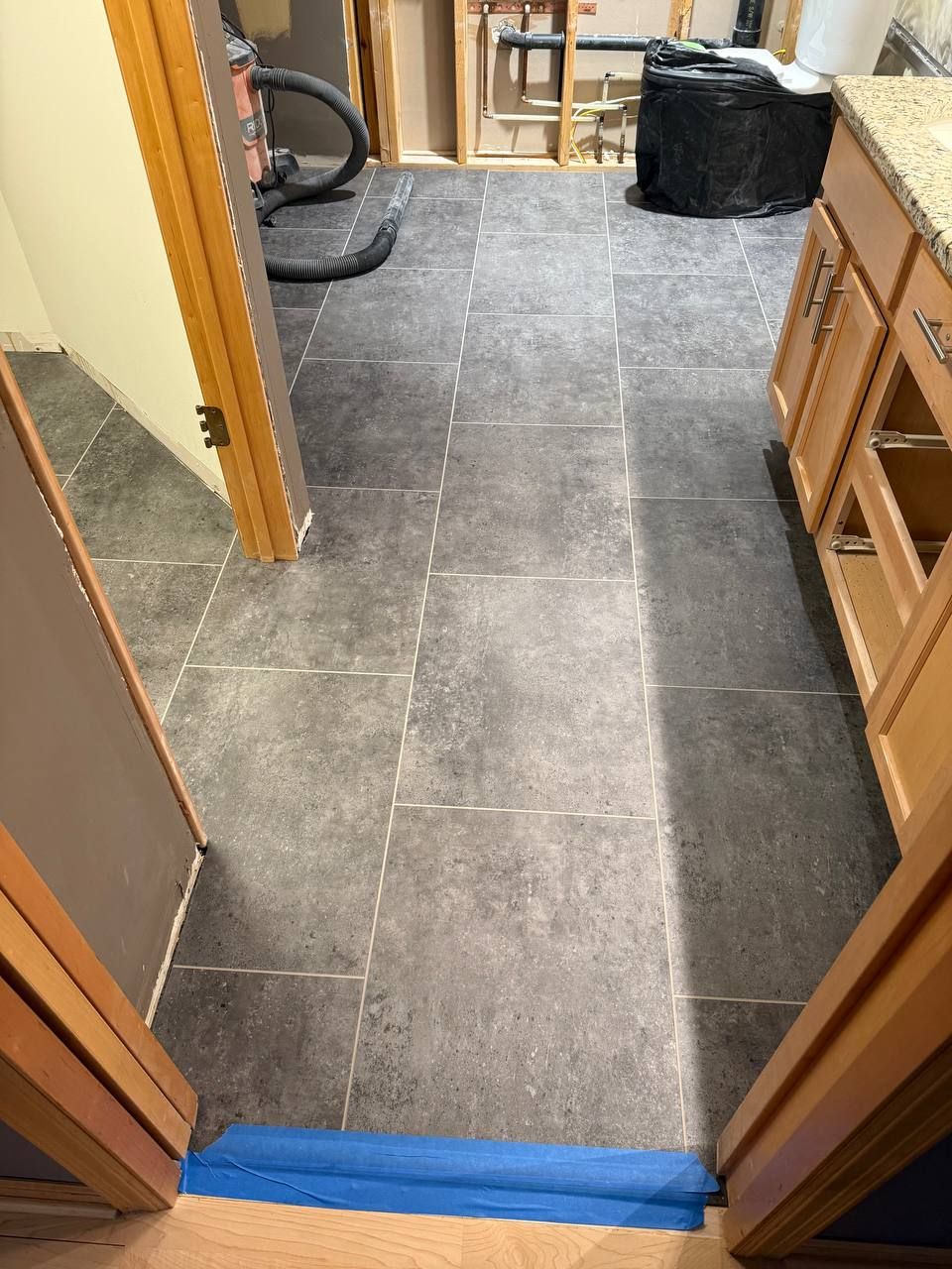 Dark gray LVP flooring with white grout lines in a kitchen during installation.
