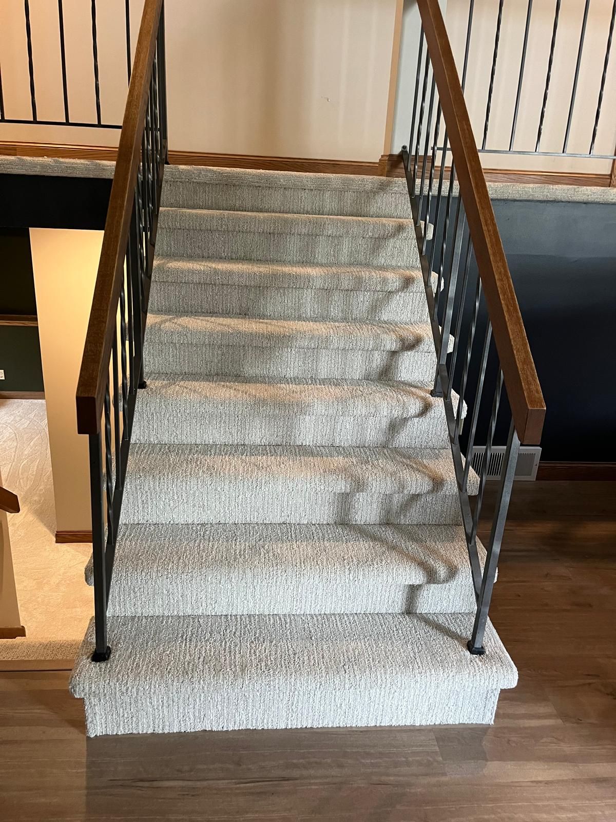 Staircase with light gray patterned carpet runner and dark wood railings.