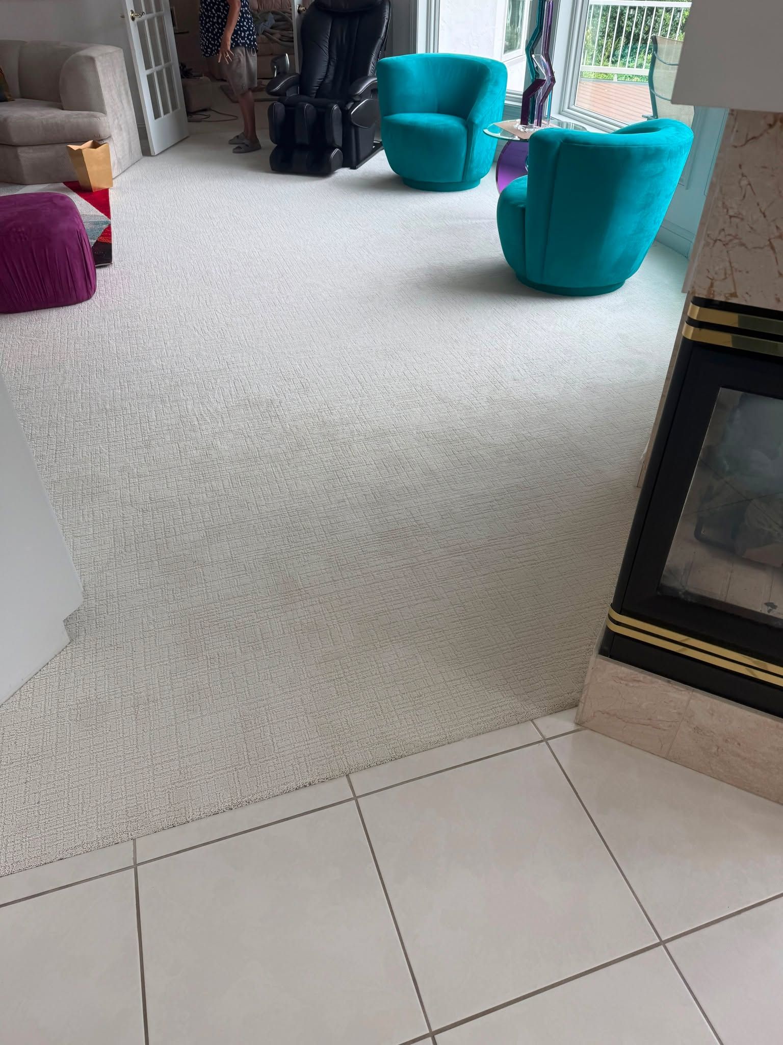 Light cream carpet installed in a living room with fireplace and transition to tile flooring.