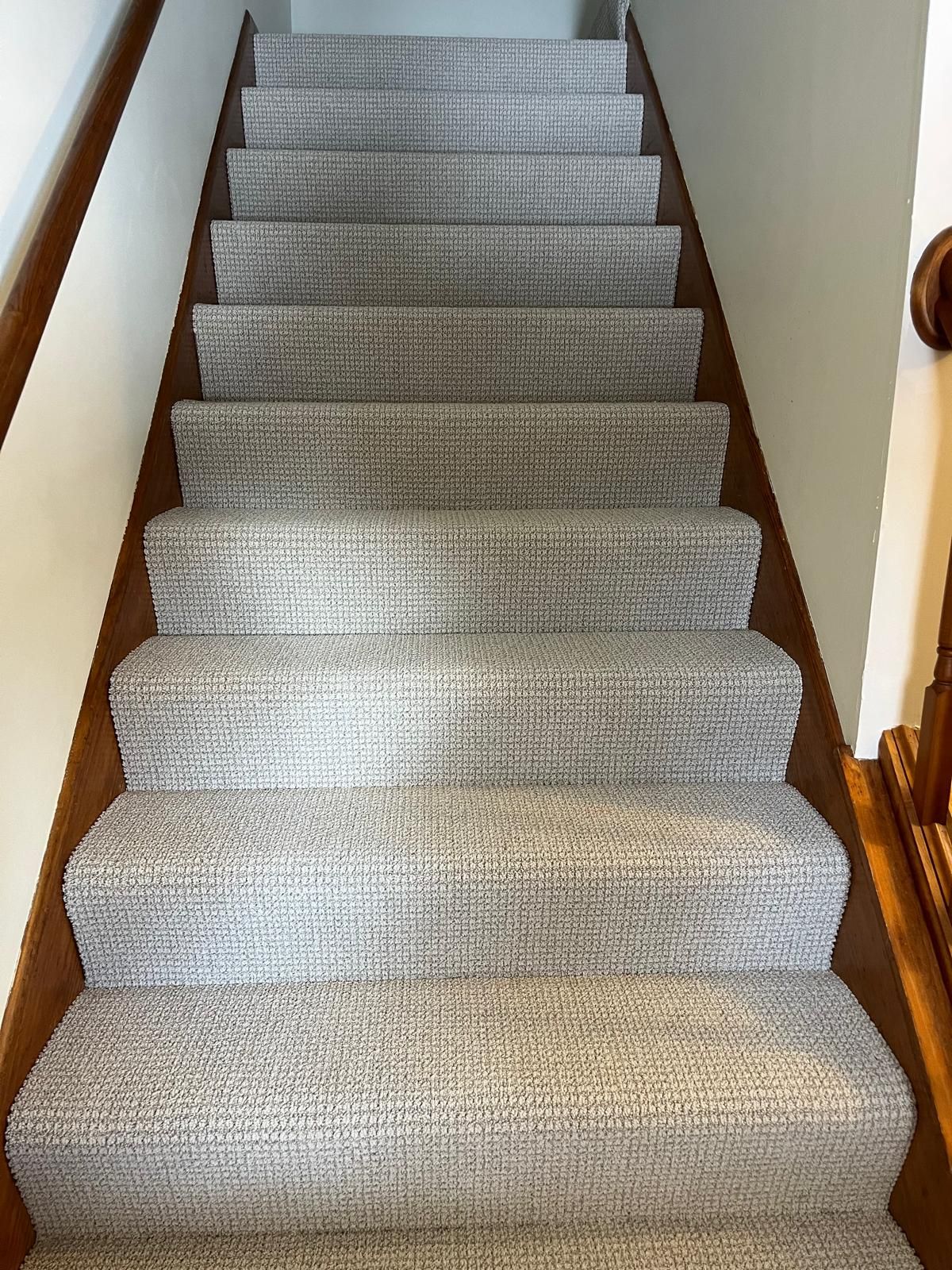 Light gray textured carpet installed on interior staircase with dark wood stair nosing.