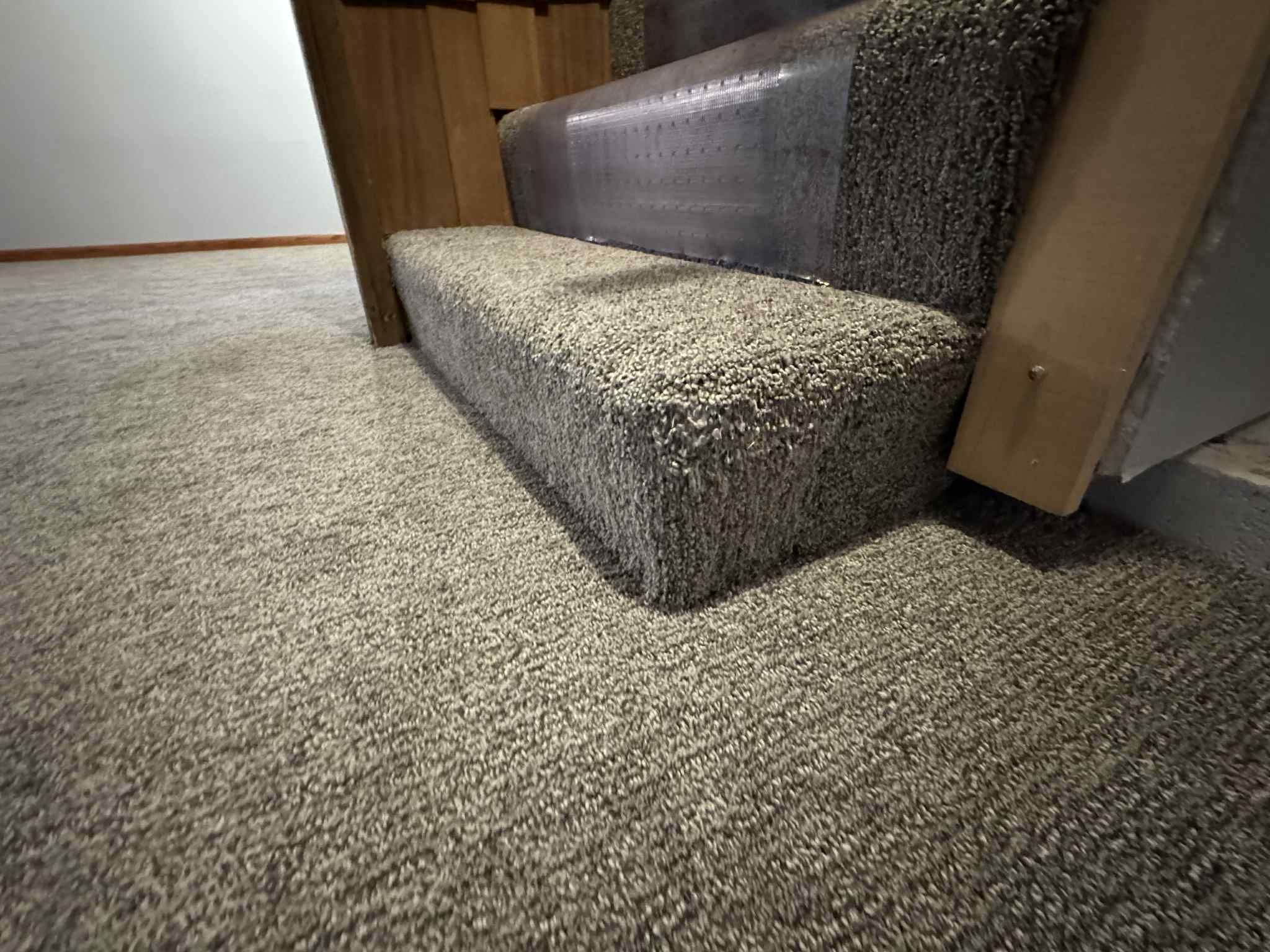 Beige textured carpet installed in a bedroom with a bed frame visible.