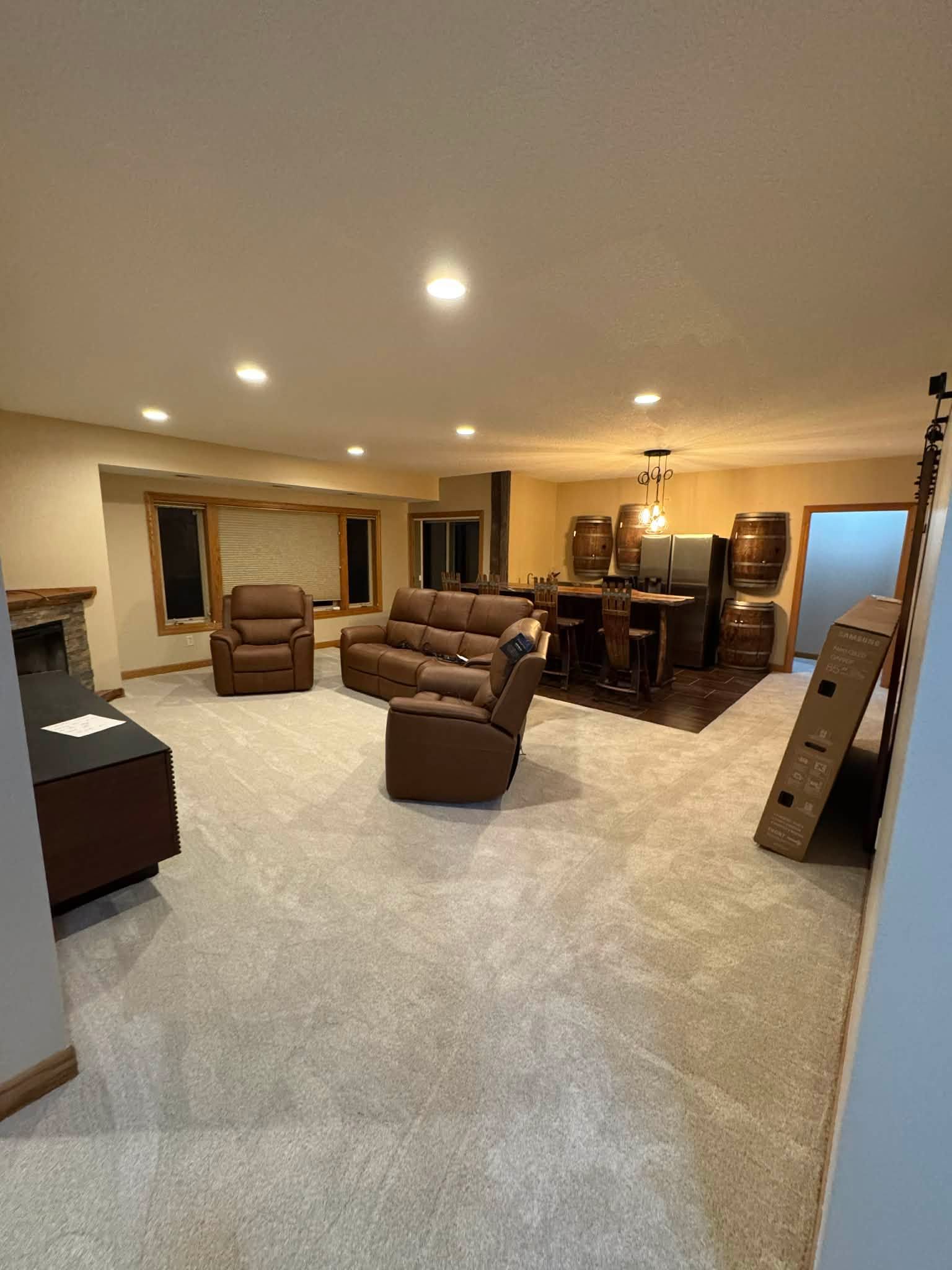 Basement with new beige carpet throughout and brown furniture arranged in seating areas.