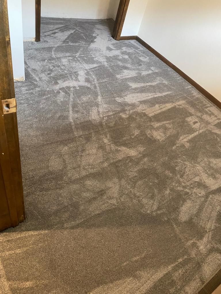 Hallway with geometric patterned carpet in gray and tan tones with wooden door frames.