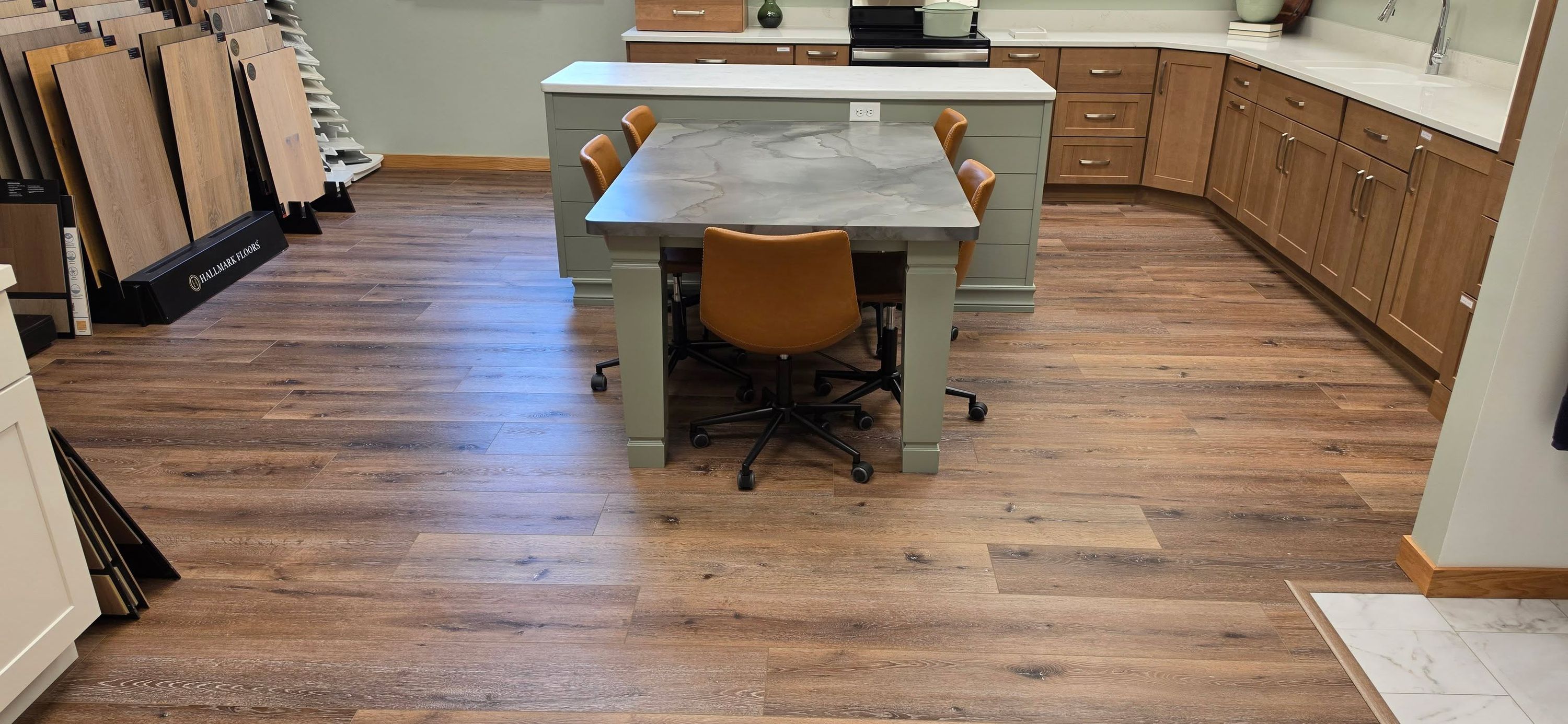 Hardwood plank flooring in a kitchen showroom display with furniture and cabinetry.