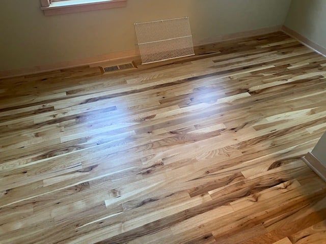 Newly installed hickory hardwood flooring with varied brown and golden tones in a bedroom with plank pattern and glossy finish.