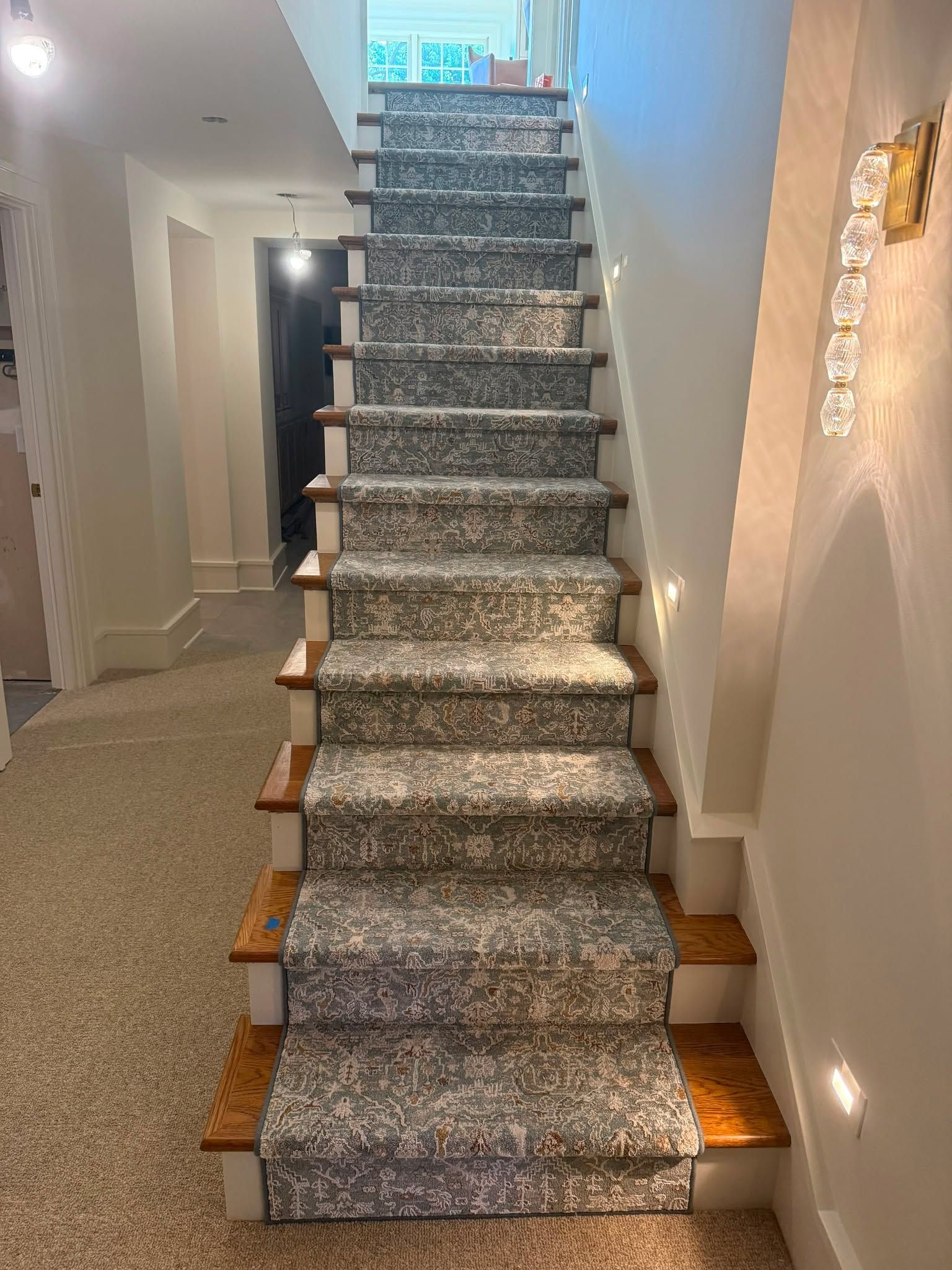 Carpeted staircase with gray patterned runner and wood nosing in residential home.