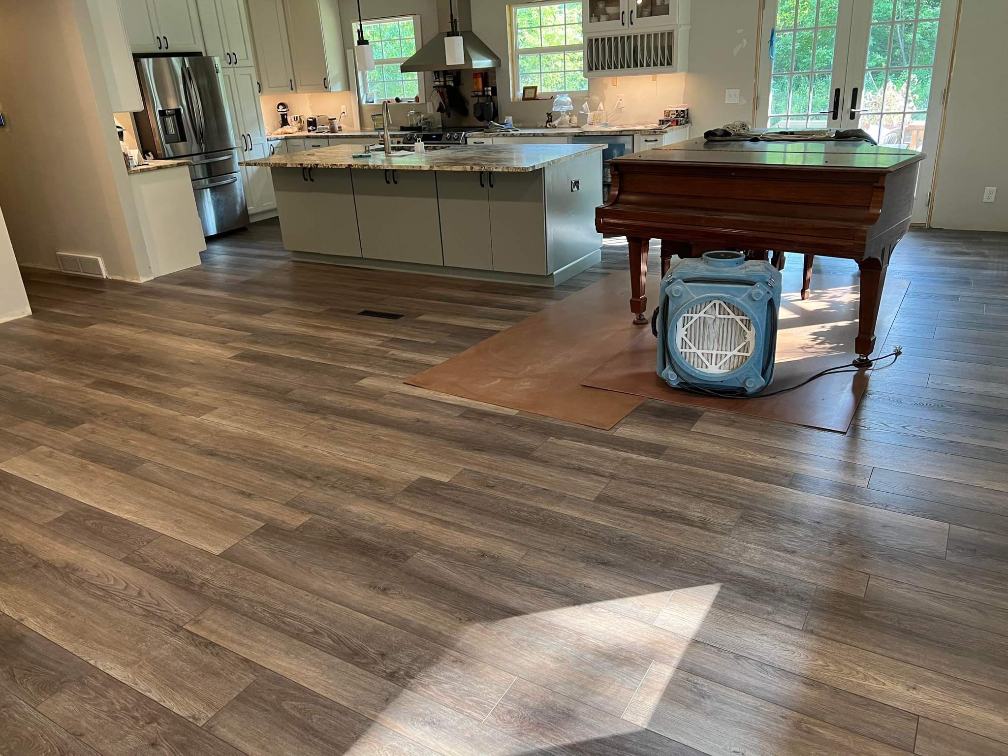 Kitchen with wide plank LVP flooring in weathered wood tones throughout open living space.