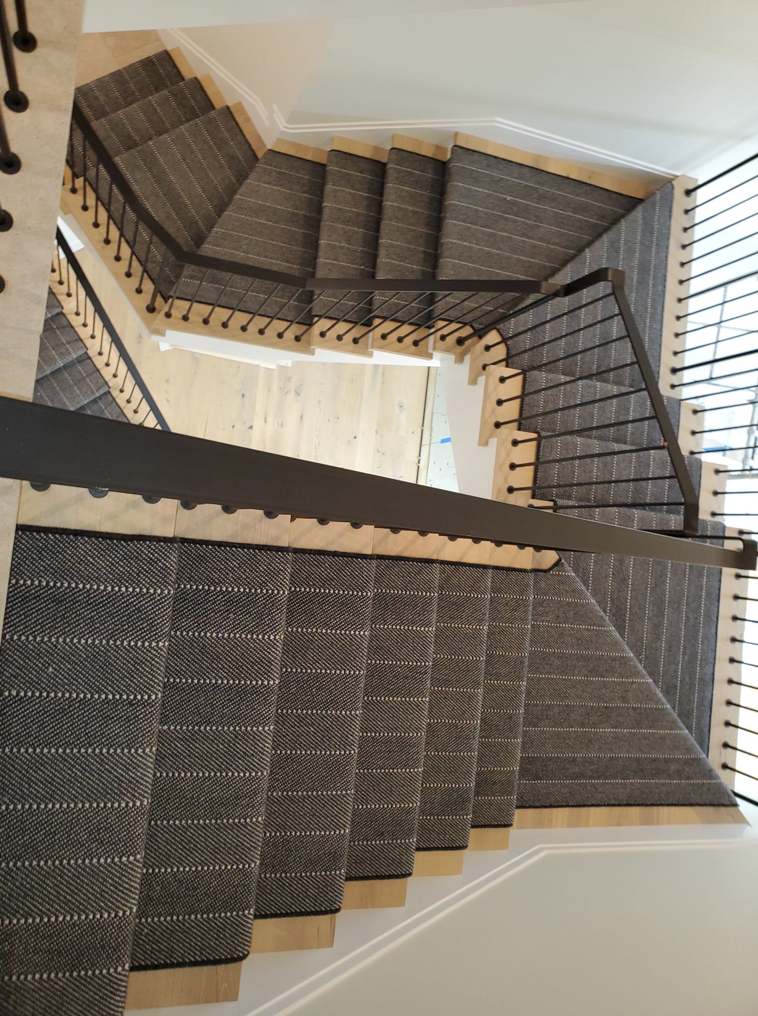 Staircase with gray wool carpet runners and wood nosing installed on multiple flights.