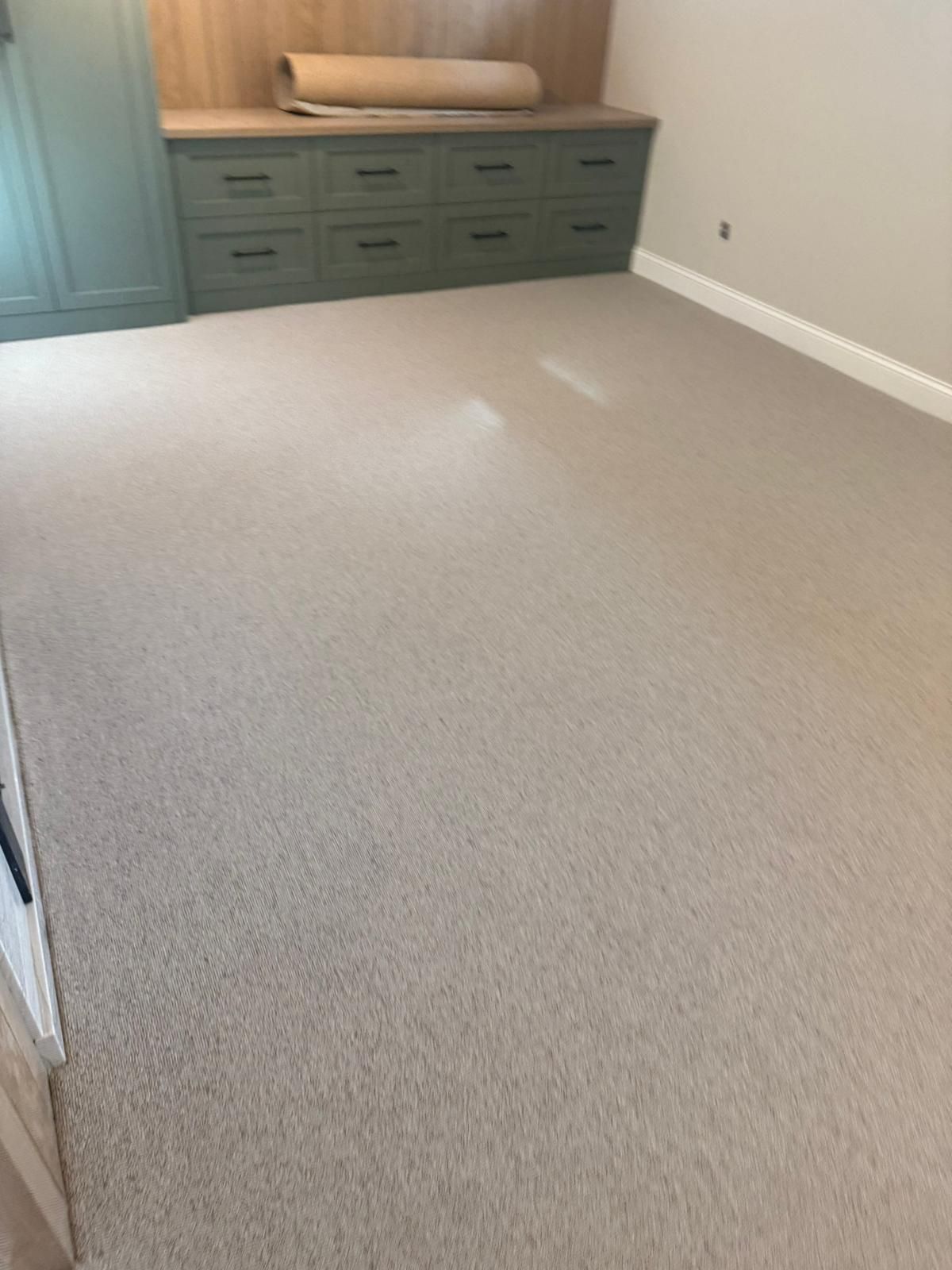 Light beige wool carpet installed in a bedroom with a green dresser and wood shelving.