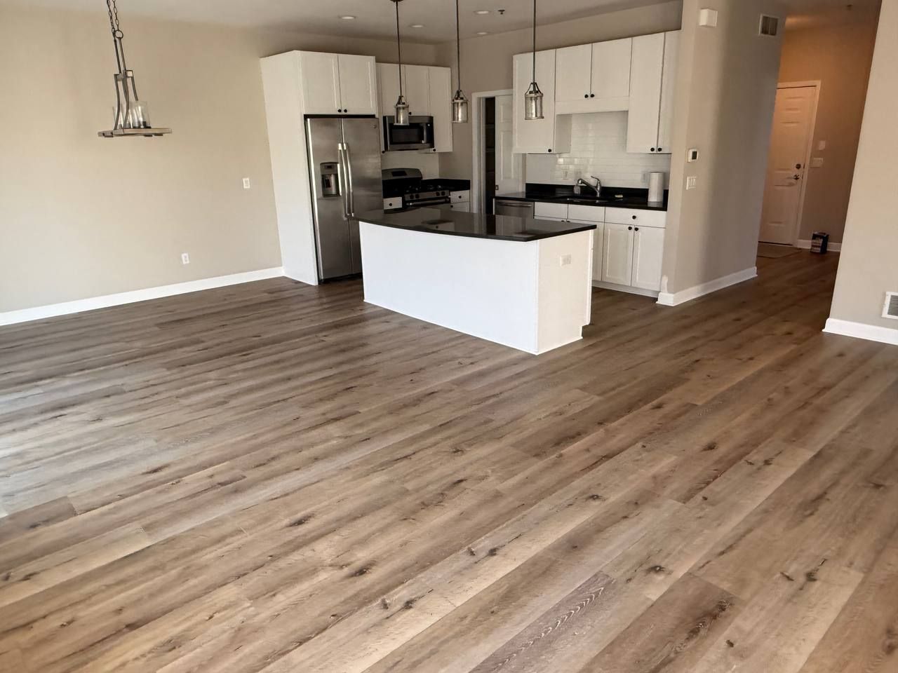 Kitchen and living area with medium-brown plank LVP flooring and white cabinetry.