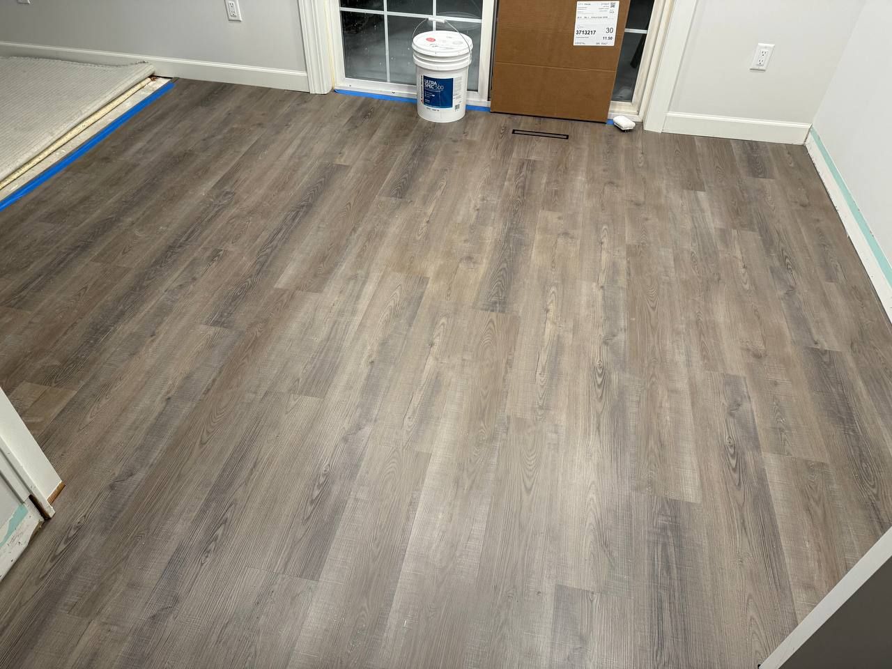Luxury vinyl plank flooring with wood-look finish being installed in a kitchen.