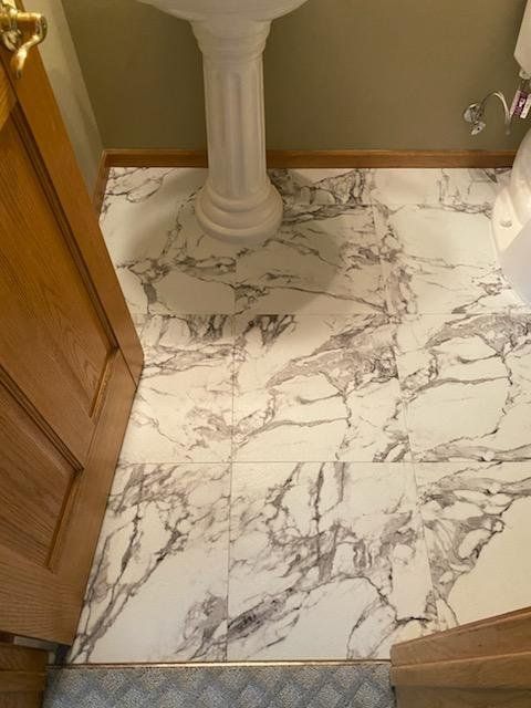 Bathroom with white and gray marble-look LVP flooring and a decorative white column.