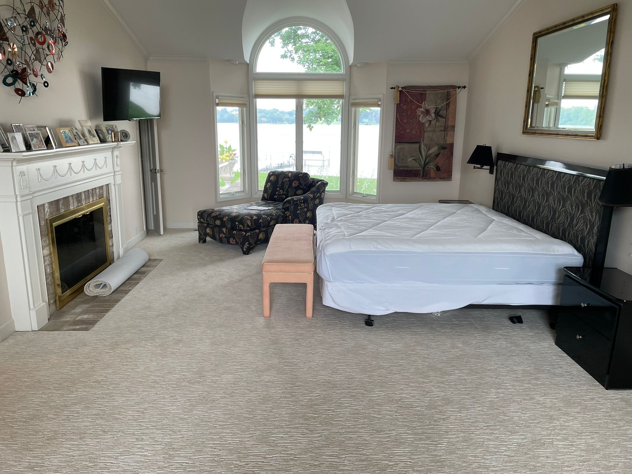Light beige carpet installed in a bedroom with a fireplace, large windows overlooking water, and water views.
