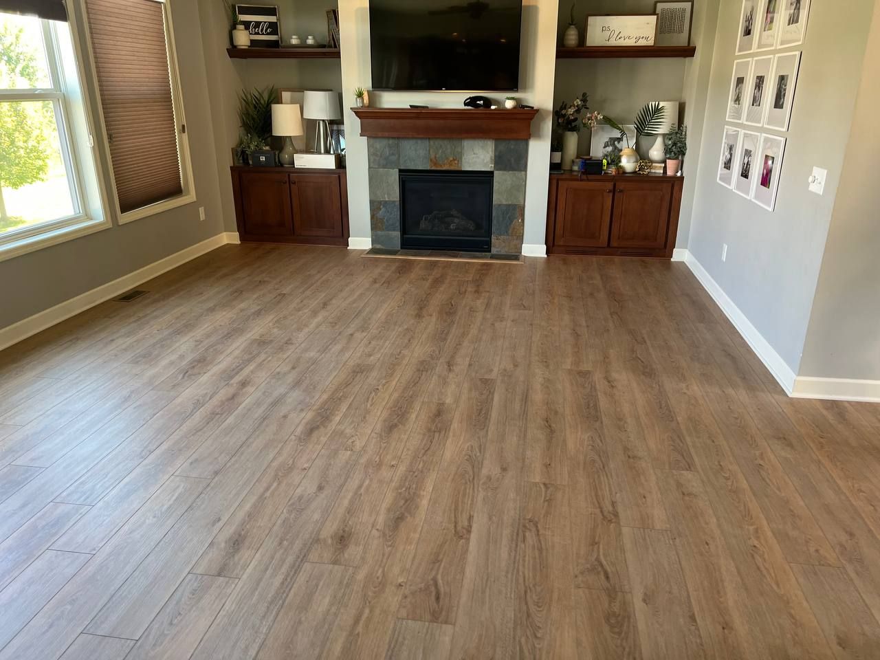 Living room with medium-toned wood-look LVP planks installed in front of a fireplace with built-in cabinetry.