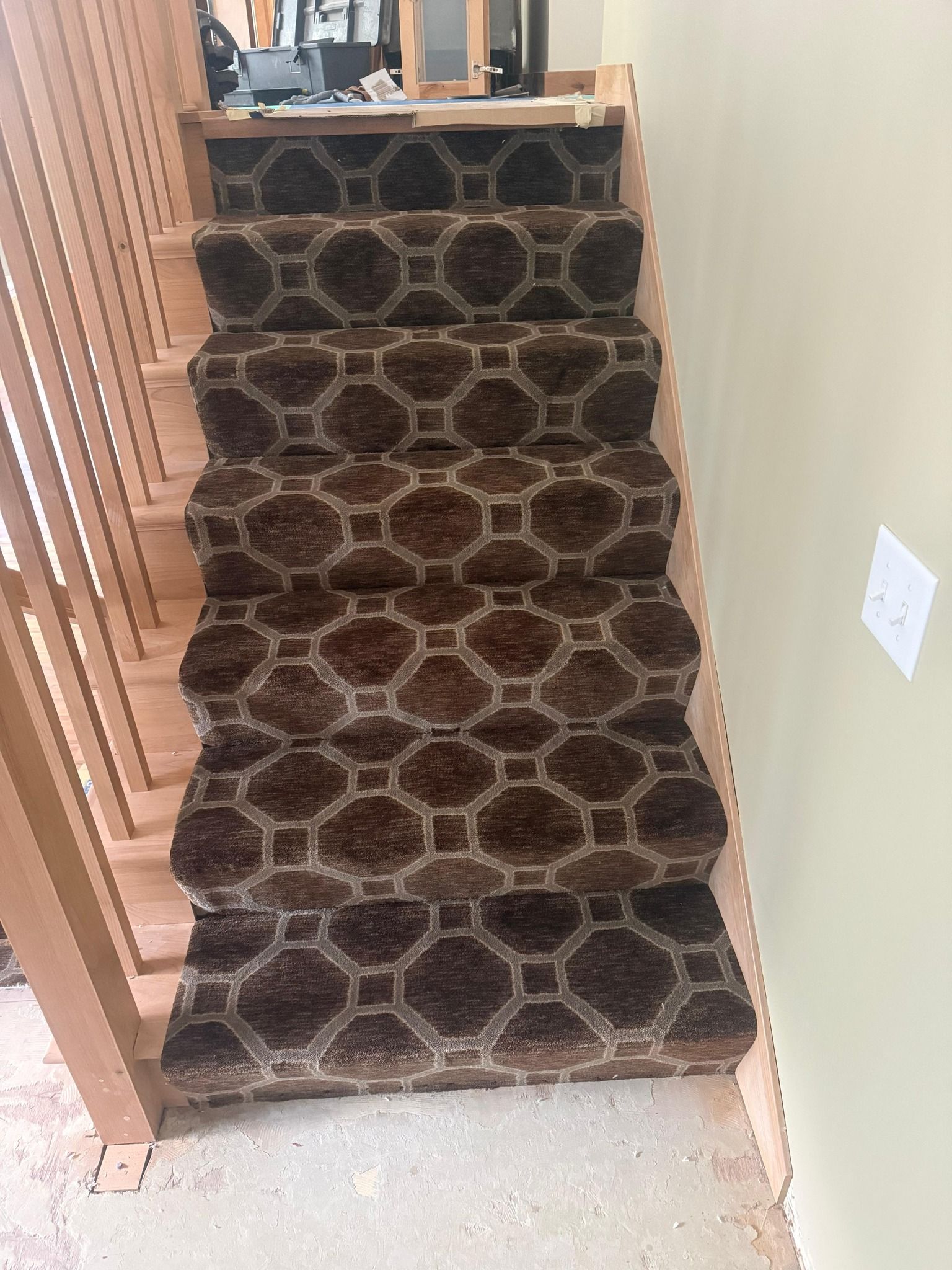 Carpet with dark brown and tan hexagonal pattern installed on residential staircase.