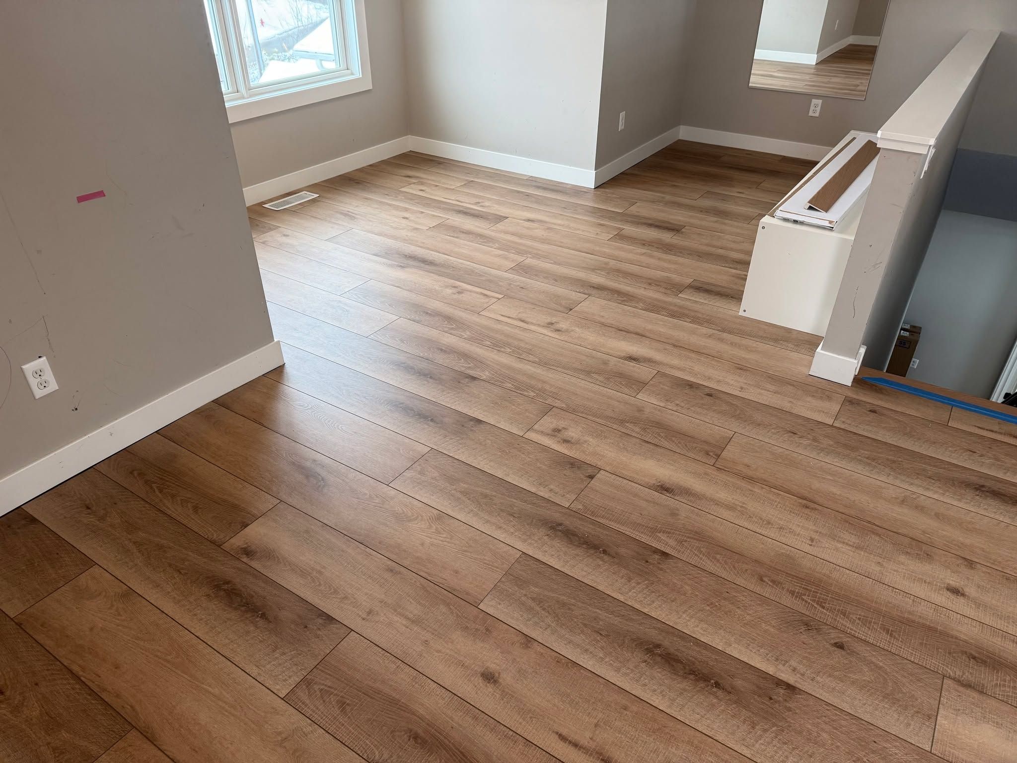Living room with medium brown luxury vinyl plank flooring installed in a staggered plank pattern.