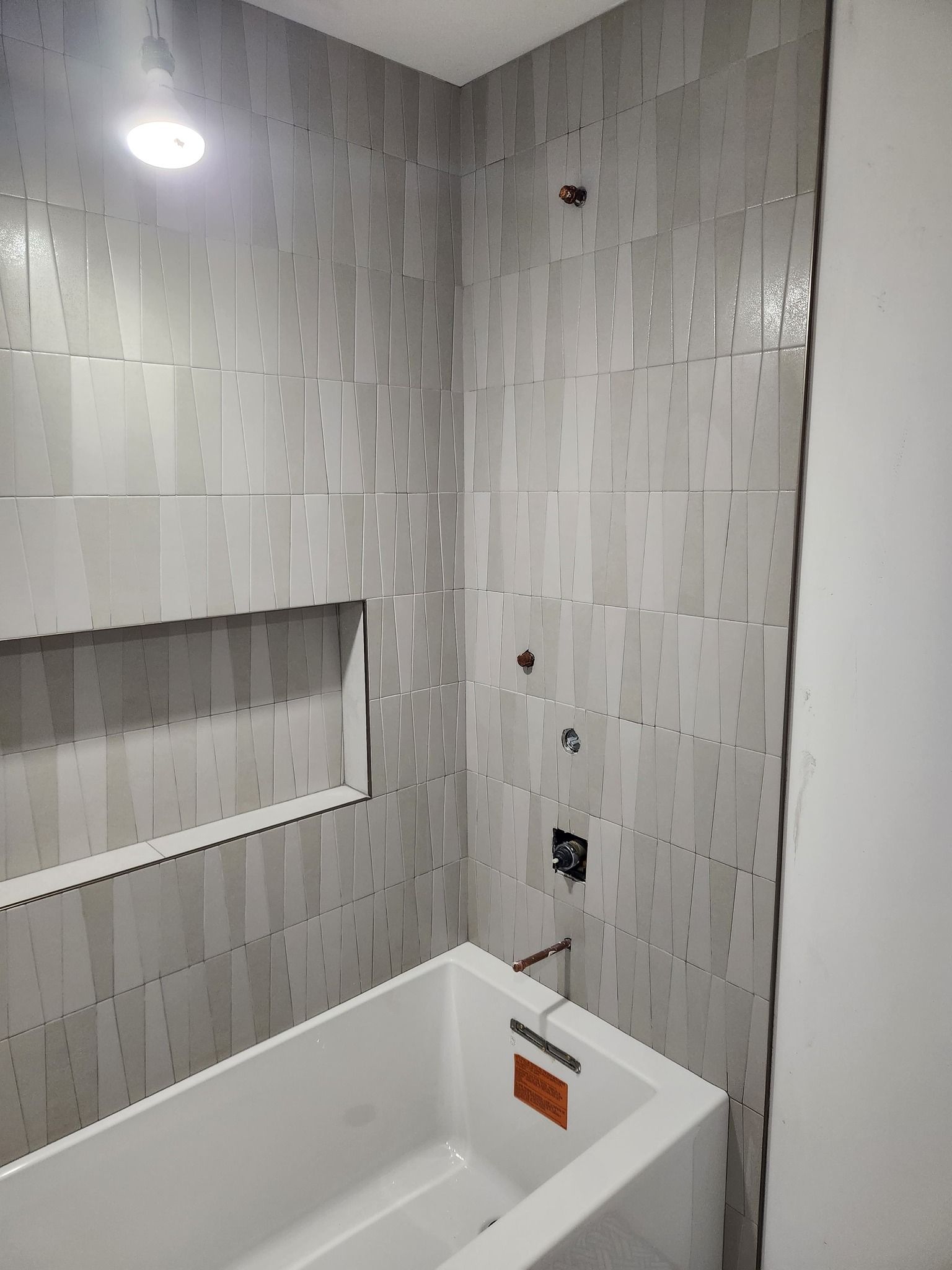 Bathroom shower with white subway tile walls and gray grout lines.