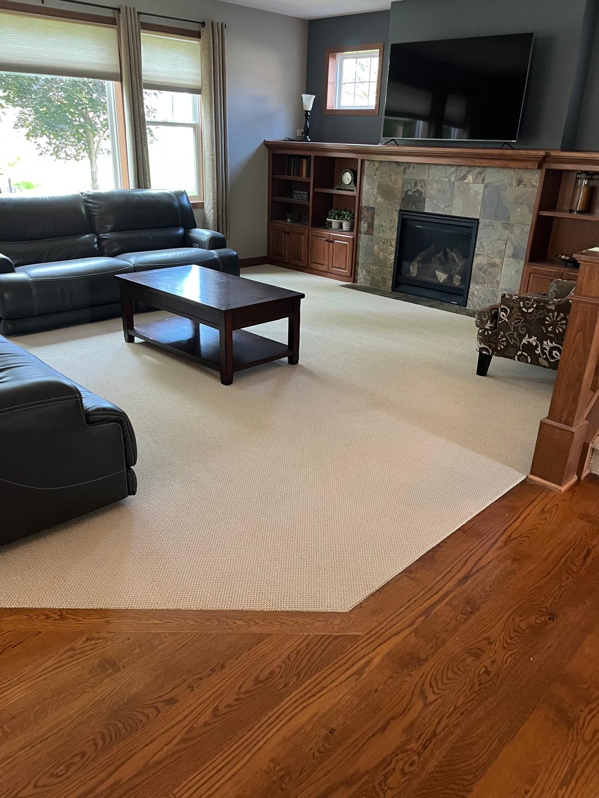 Light beige textured carpet installed in a living room with hardwood flooring visible at the transition edge.