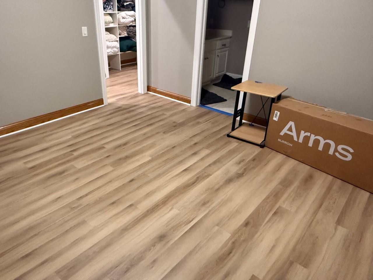 Light wood-look luxury vinyl plank flooring installed in a bedroom with white trim and open closet doors.