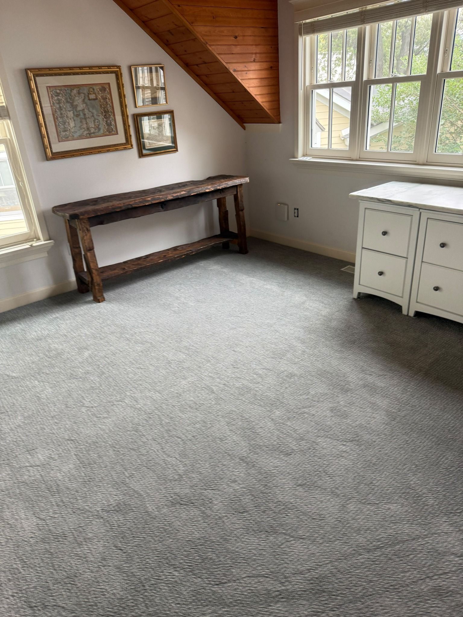 Bedroom with new light gray textured carpet, wooden vaulted ceiling, and white dresser.