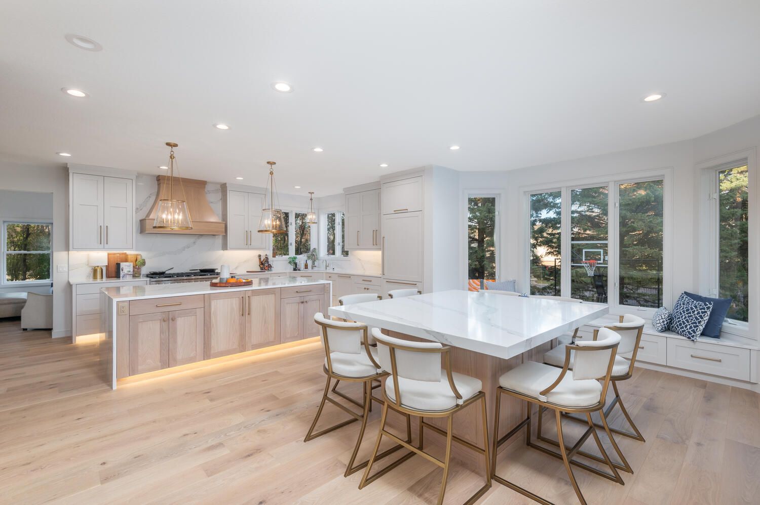 Light hardwood plank flooring in a kitchen and dining area with white cabinetry and an island.